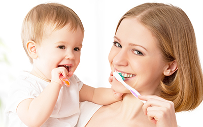 A mother and baby girl brushing their teeth together