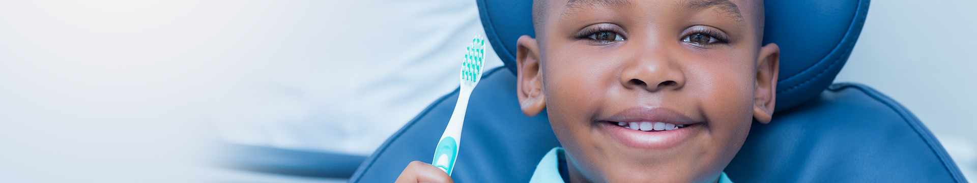 Young child in dental office smiling with toothbrush