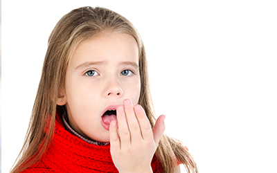 A young girl blowing into her hand to smell her breath