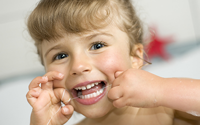 A child flossing her teeth