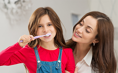 A parent helping their young child brush their teeth