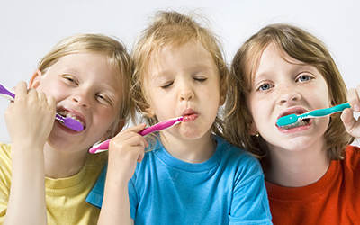 Three young kids brushing their teeth together