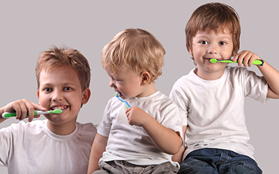 Three young boys brushing their teeth