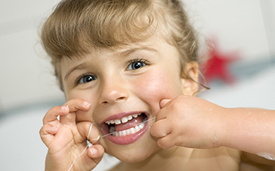 A young girl flossing her teeth